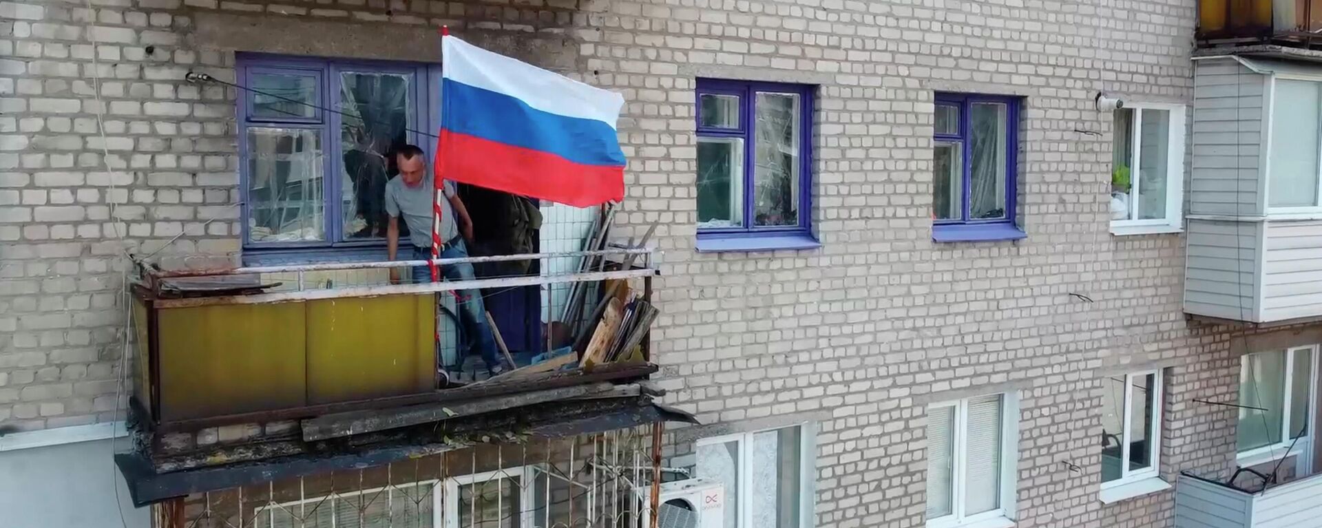 Homem coloca bandeira russa na varanda de edifício residencial em Lisichansk, na República Popular de Lugansk (RPL), em 4 de julho de 2022 - Sputnik Brasil, 1920, 05.09.2022
