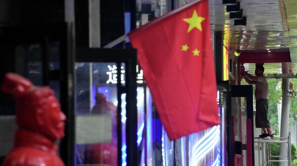 Trabalhador em plataforma perto de bandeira chinesa em Pequim, na China, em 15 de julho de 2022 - Sputnik Brasil