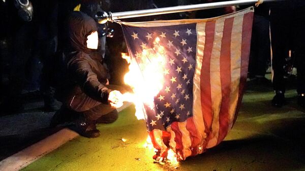 Manifestante põe fogo em bandeira americana durante protesto contra a desigualdade racial e a violência policial em Portland. Oregon, 27 de julho de 2020 - Sputnik Brasil