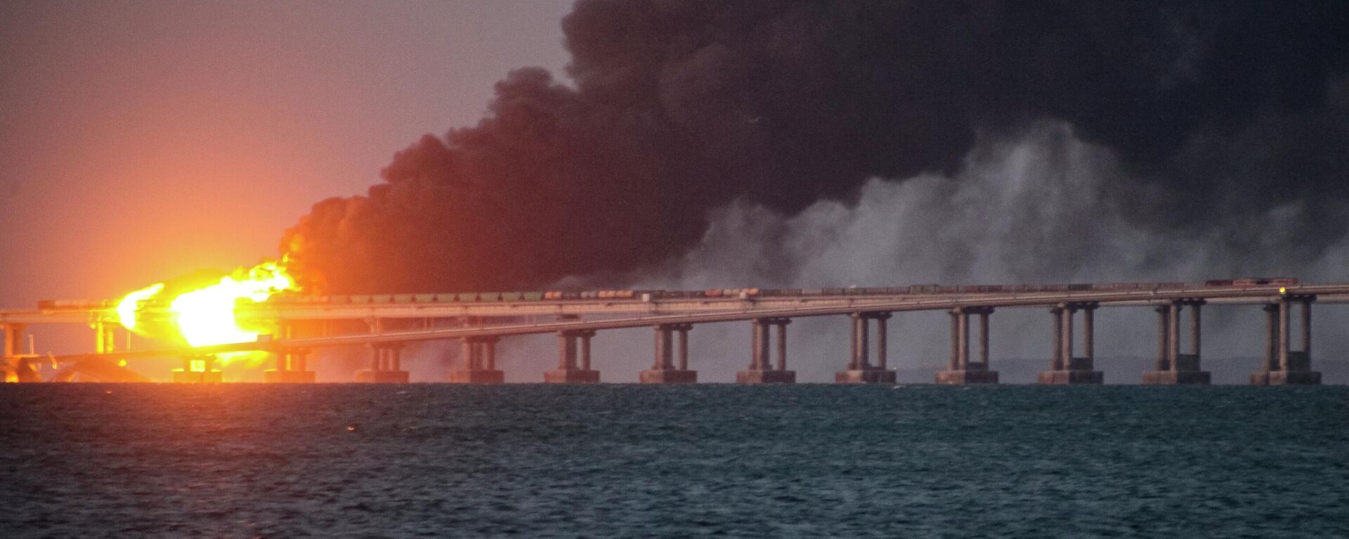 Chamas e fumaça sobem da Ponte da Crimeia, que conecta a Rússia à península da Crimeia, após explosão, em 8 de outubro de 2022 - Sputnik Brasil, 1920, 20.07.2023