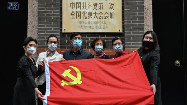 Pessoas posam para foto com a bandeira do Partido Comunista junto do prédio em que em julho de 1921 foi realizado o primeiro encontro formal do Partido Comunista da China em Xangai, 16 de outubro de 2022 - Sputnik Brasil