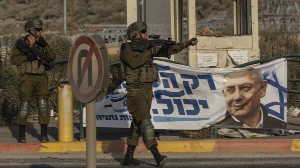 Soldados israelenses gesticulam para um veículo em Tapuah Junction, ao lado de um pôster de campanha para o ex-primeiro-ministro israelense Benjamin Netanyahu, perto da cidade de Nablus, na Cisjordânia, 16 de outubro de 2022 - Sputnik Brasil