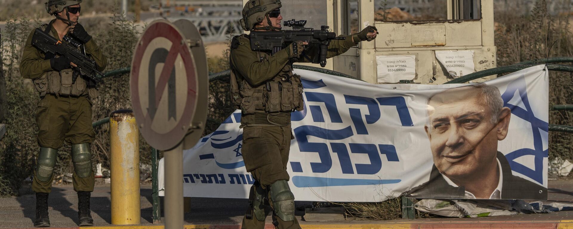 Soldados israelenses gesticulam para veículo em Tapuah Junction, ao lado de um pôster de campanha do ex-primeiro-ministro israelense Benjamin Netanyahu, perto da cidade de Nablus, na Cisjordânia, em 16 de outubro de 2022 - Sputnik Brasil, 1920, 17.05.2026