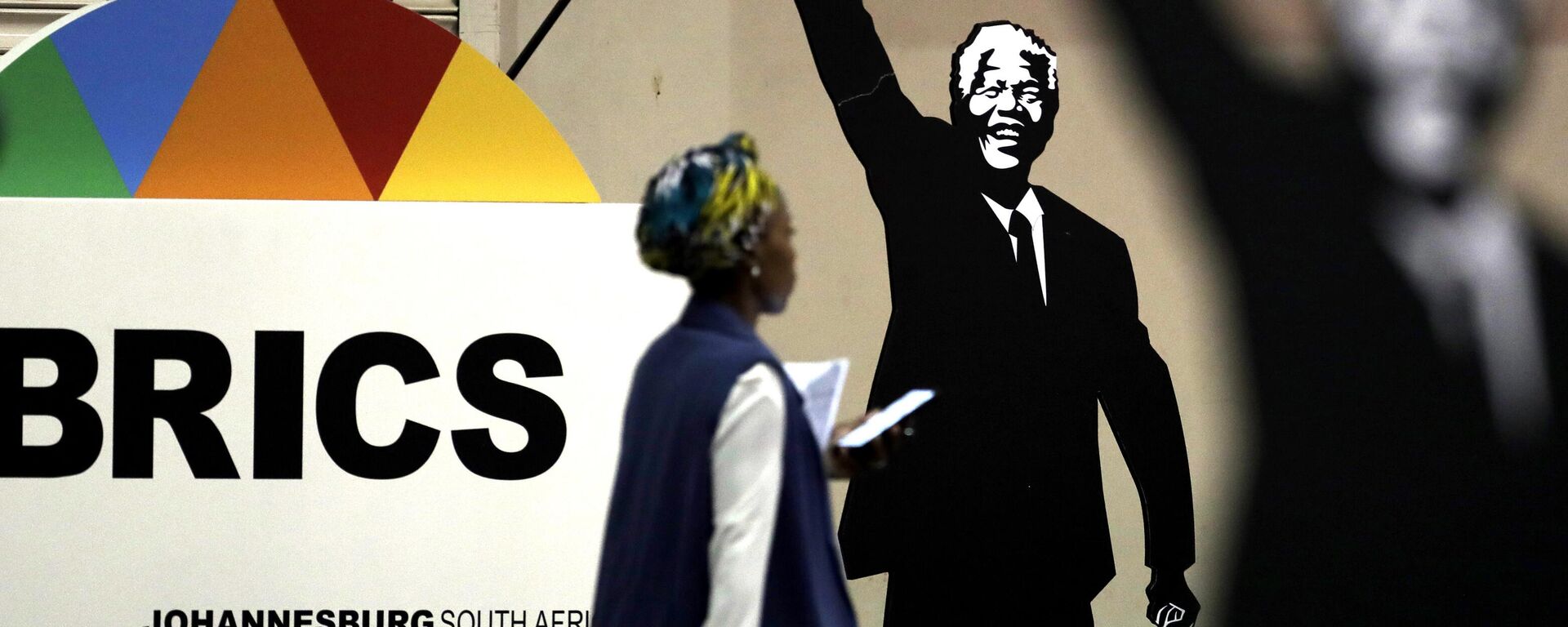 Mulher passa diante de cartaz em homenagem ao ex-presidente da África do Sul Nelson Mandela durante encontro do BRICS em Joanesburgo. África do Sul, 27 de julho de 2018 - Sputnik Brasil, 1920, 26.04.2024