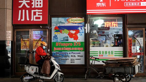 Um entregador fica em frente a um outdoor anunciando transporte logístico internacional para a Rússia, do lado de fora de uma loja de conveniência no Ritan International Trade Center em Pequim em 22 de março de 2022 - Sputnik Brasil