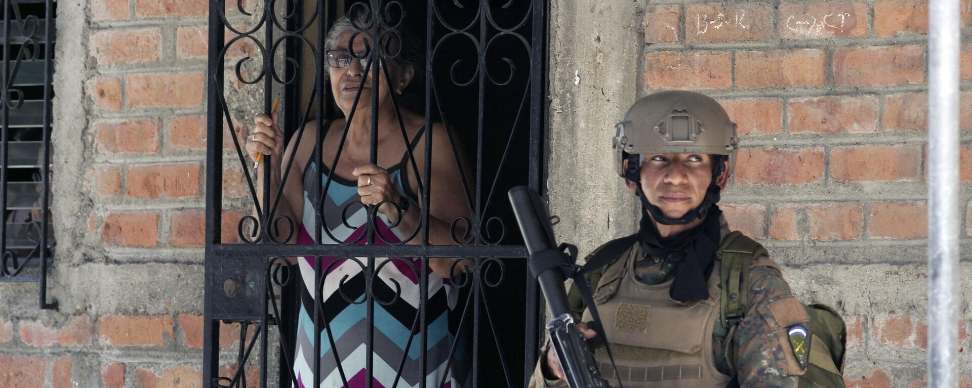 Uma moradora em sua casa ao lado de um soldado que participa de operação em busca de membros de gangues, em Soyapango, El Salvador, 3 de dezembro de 2022 - Sputnik Brasil, 1920, 03.12.2022
