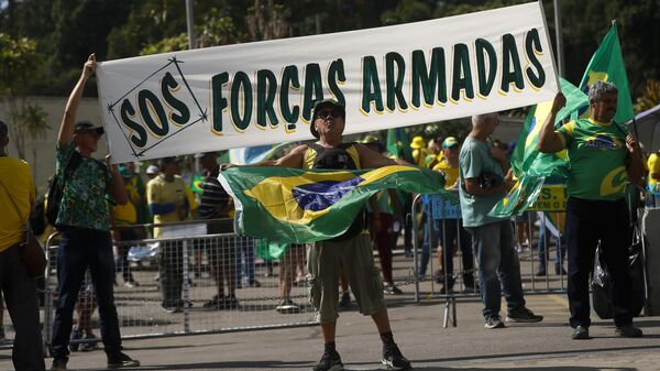 Apoiadores do presidente brasileiro Jair Bolsonaro seguram um cartaz com a mensagem em português: S.O.S Forças Armadas durante um protesto contra o resultado das eleições presidenciais, 15 de novembro de 2022 - Sputnik Brasil