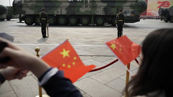 Espetadores acenam com bandeiras chinesas enquanto veículos militares DF-41, capazes de transportar ogivas nucleares, passam durante desfile por ocasião do 70º aniversário da fundação do Partido Comunista chinês, Pequim, 1 de outubro de 2019 - Sputnik Brasil