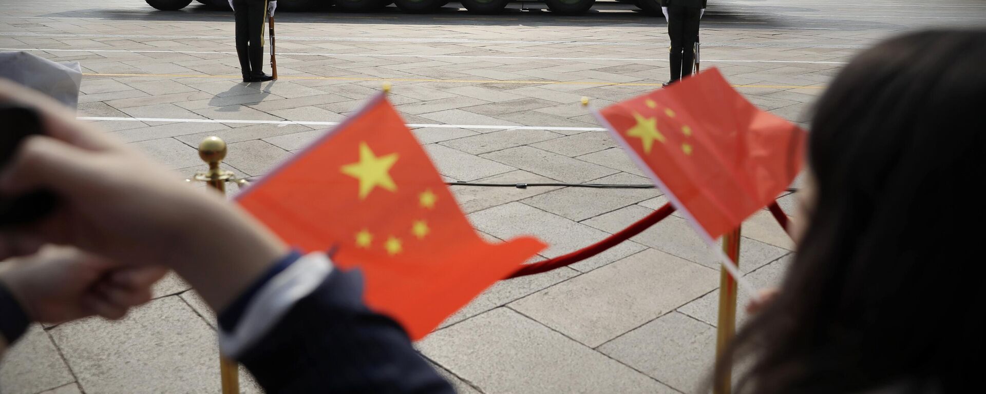 Espetadores acenam com bandeiras chinesas enquanto veículos militares DF-41, capazes de transportar ogivas nucleares, passam durante desfile por ocasião do 70º aniversário da fundação do Partido Comunista chinês, Pequim, 1 de outubro de 2019 - Sputnik Brasil, 1920, 28.04.2023
