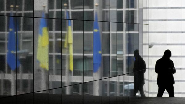 As bandeiras da Ucrânia e da União Europeia são refletidas em uma parede de mármore enquanto um visitante caminha antes de uma sessão plenária extraordinária sobre a Ucrânia no Parlamento Europeu em Bruxelas, 1º de março de 2022 - Sputnik Brasil