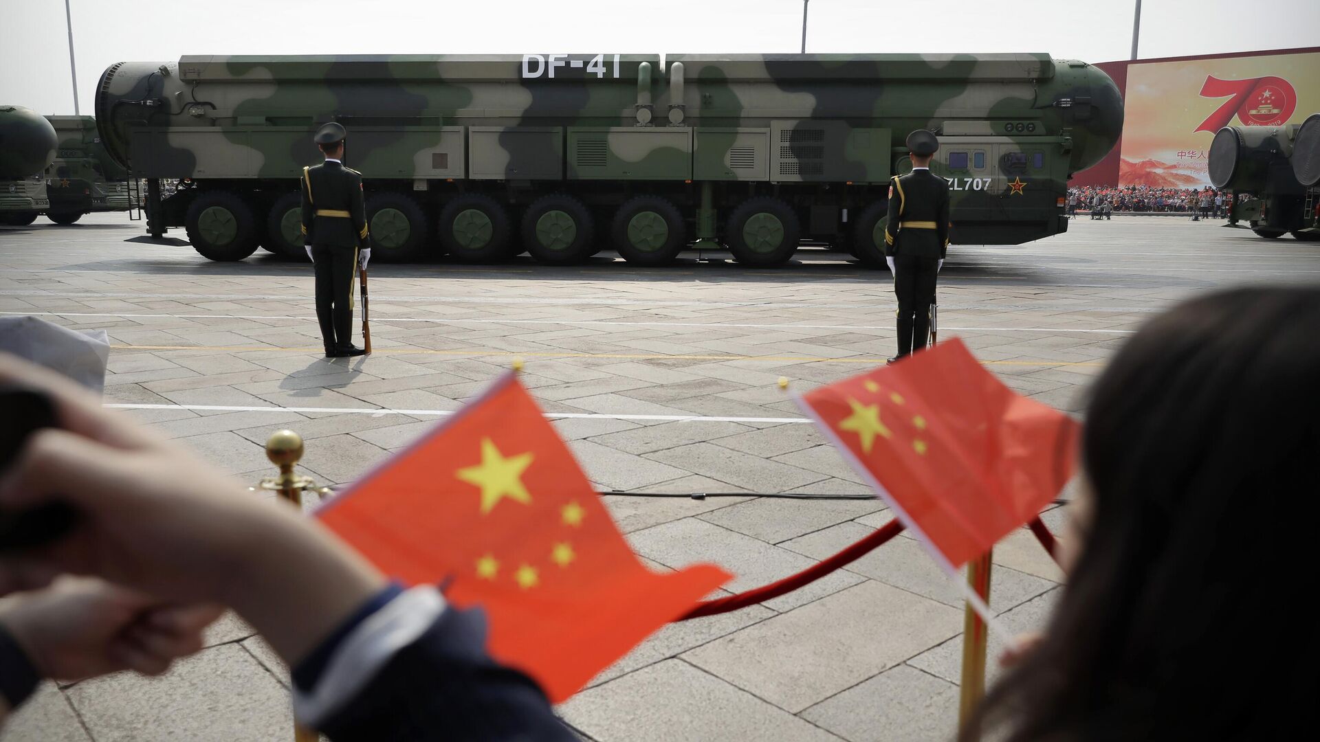 Espectadores agitam bandeiras chinesas enquanto observam passagem de veículos militares carregando mísseis balísticos DF-41 capazes de usar ogivas nucleares em parada comemorativa do 70º aniversário da República Popular da China em Pequim, China, 1º de outubro de 2019 - Sputnik Brasil, 1920, 12.12.2022