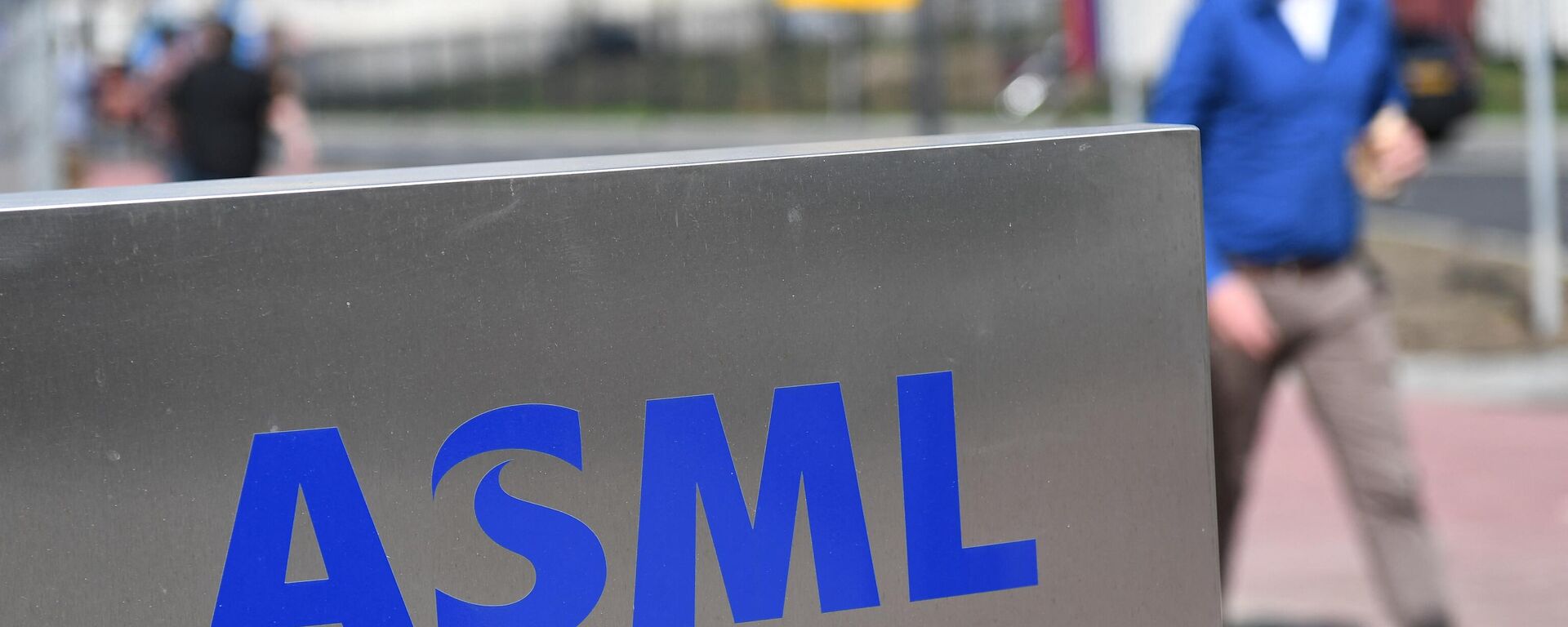 Empregado da empresa de semicondutores ASML passa ao lado de seu logotipo em Veldhoven, Países Baixos, 17 de abril de 2018 - Sputnik Brasil, 1920, 15.12.2022