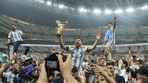 O argentino Lionel Messi comemora com o troféu diante dos torcedores depois de vencer a final da Copa do Mundo de futebol entre Argentina e França, 18 de dezembro de 2022 - Sputnik Brasil