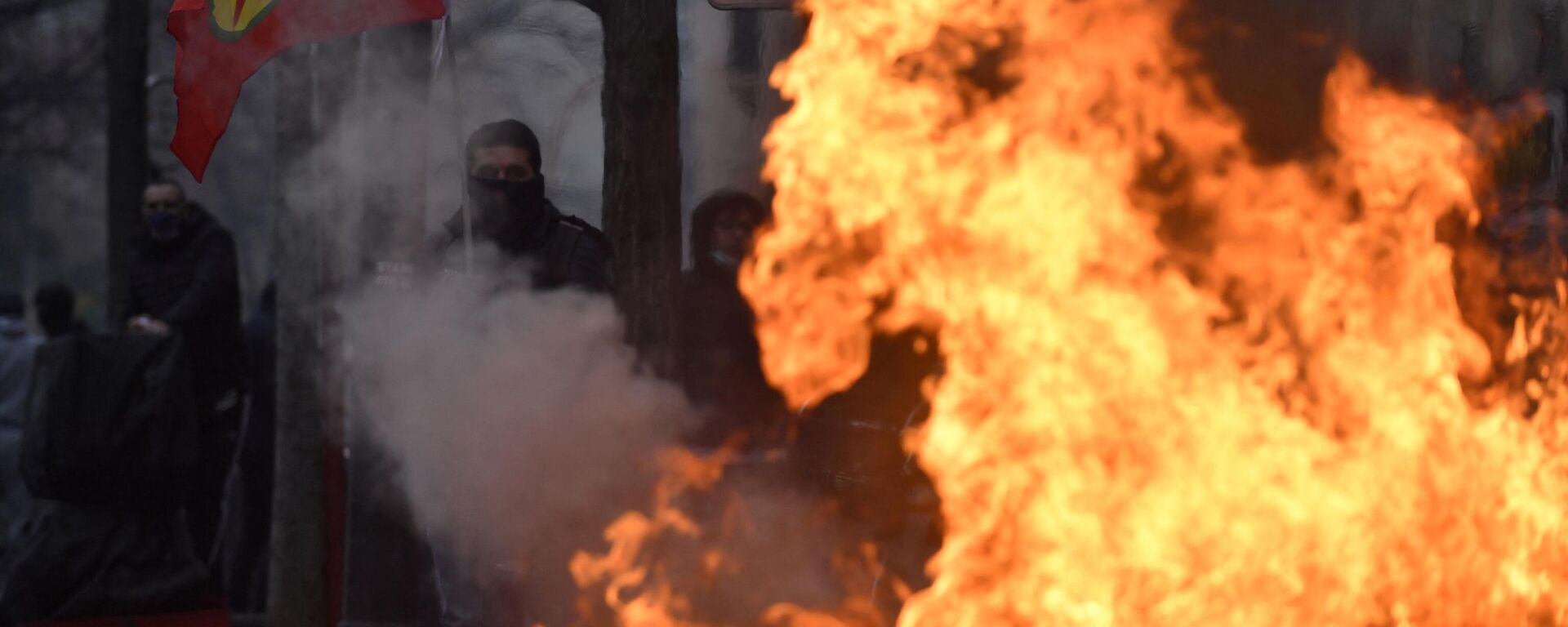 Um manifestante segura uma bandeira do Partido dos Trabalhadores do Curdistão (PKK) atrás das chamas de um incêndio provocado durante confrontos após uma manifestação de apoiadores e membros da comunidade curda, um dia depois que um atirador abriu fogo em um centro cultural curdo matando três pessoas, na Place de la Republique em Paris, 24 de dezembro de 2022 - Sputnik Brasil, 1920, 25.12.2022