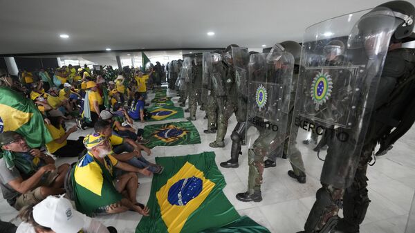 Manifestantes bolsonaristas sentam em frente a agentes do Exército no Palácio do Planalto em meio à invasão de prédios públicos na capital brasileira, Brasília, 8 de janeiro de 2023 - Sputnik Brasil