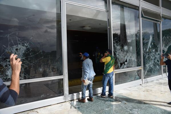 Manifestantes bolsonaristas diante de vidraças destruídas no Supremo Tribunal Federal (STF), em meio à invasão da Praça dos Três Poderes e de prédios públicos em Brasília (DF), em 8 de janeiro de 2023 - Sputnik Brasil