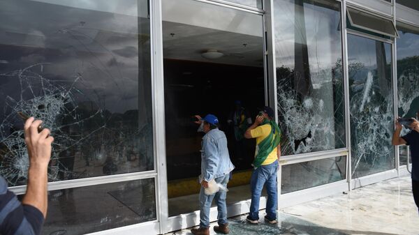 Manifestantes bolsonaristas diante de vidraças destruídas no Supremo Tribunal Federal (STF), em meio à invasão da Praça dos Três Poderes e de prédios públicos. Brasília (DF), 8 de janeiro de 2023 - Sputnik Brasil