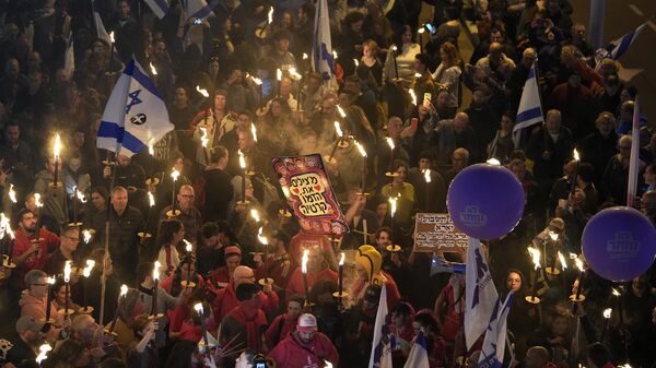 Israelenses carregam tochas em um protesto contra o primeiro-ministro israelense, Benjamin Netanyahu, e seu governo, que seus oponentes dizem ameaçar a democracia e as liberdades. Tel Aviv, Israel, 21 de janeiro de 2023 - Sputnik Brasil