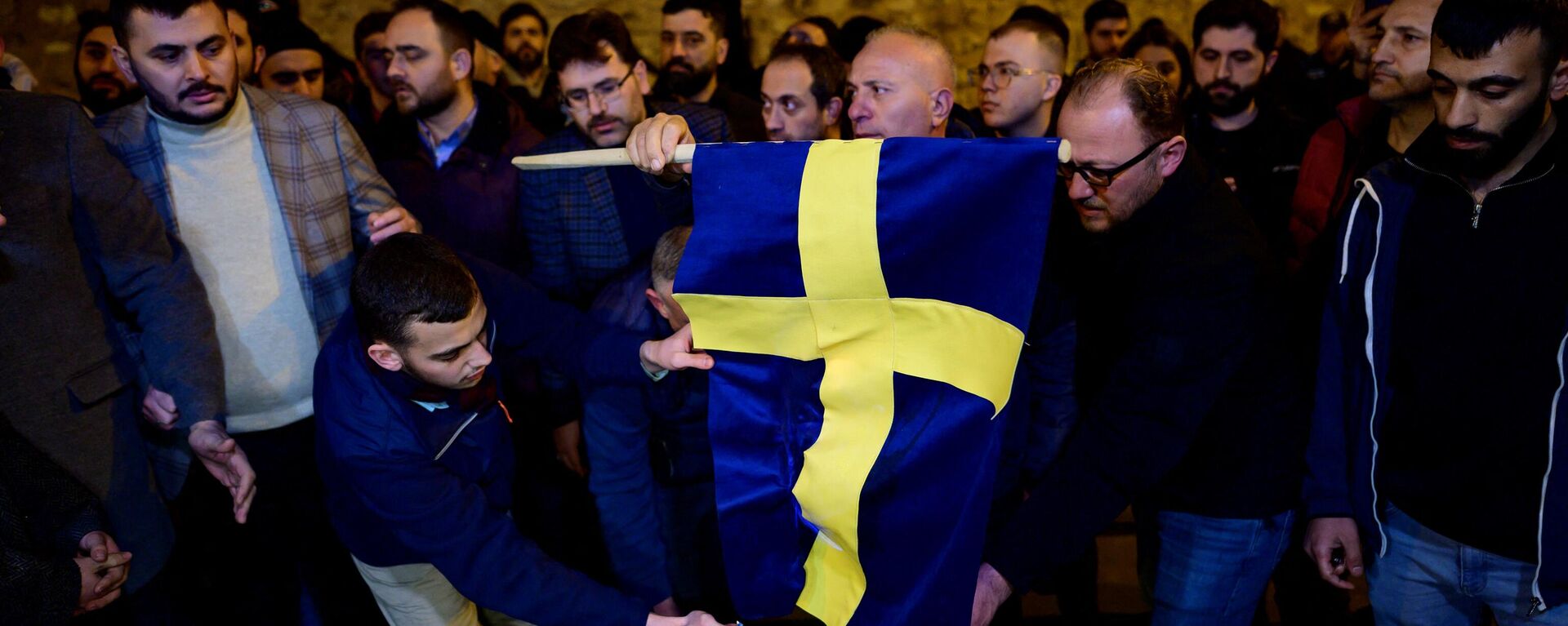 Manifestantes queimam a bandeira da Suécia em frente ao consulado geral da Suécia em Istambul depois que Rasmus Paludan, líder do partido político de extrema-direita dinamarquês Steam Kurs (Linha Dura), que também tem cidadania sueca, queimou uma cópia do Alcorão perto da embaixada da Turquia em Estocolmo, 21 de janeiro de 2023 - Sputnik Brasil, 1920, 22.01.2023