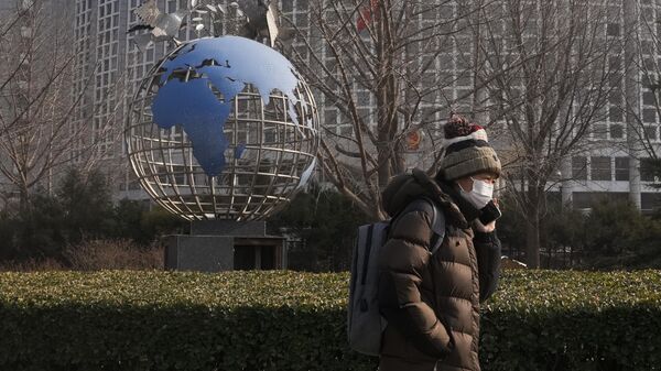 Mulher passa ao lado de escultura de globo junto do prédio do Ministério das Relações Exteriores em Pequim, China, 6 de fevereiro de 2023 - Sputnik Brasil