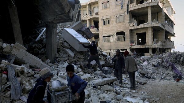 Pessoas removem móveis e eletrodomésticos de um prédio desabado após um terremoto ter devastado a Síria e a Turquia, entre as cidades entrando Jinderis, na província de Aleppo, Síria - Sputnik Brasil