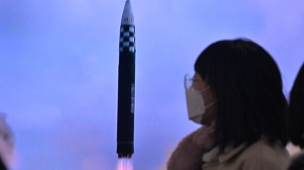 Mulher passa ao lado de tela televisiva mostrando um lançamento de míssil norte-coreano, em uma estação de trem de Seul, Coreia do Sul, 18 de fevereiro de 2023 - Sputnik Brasil