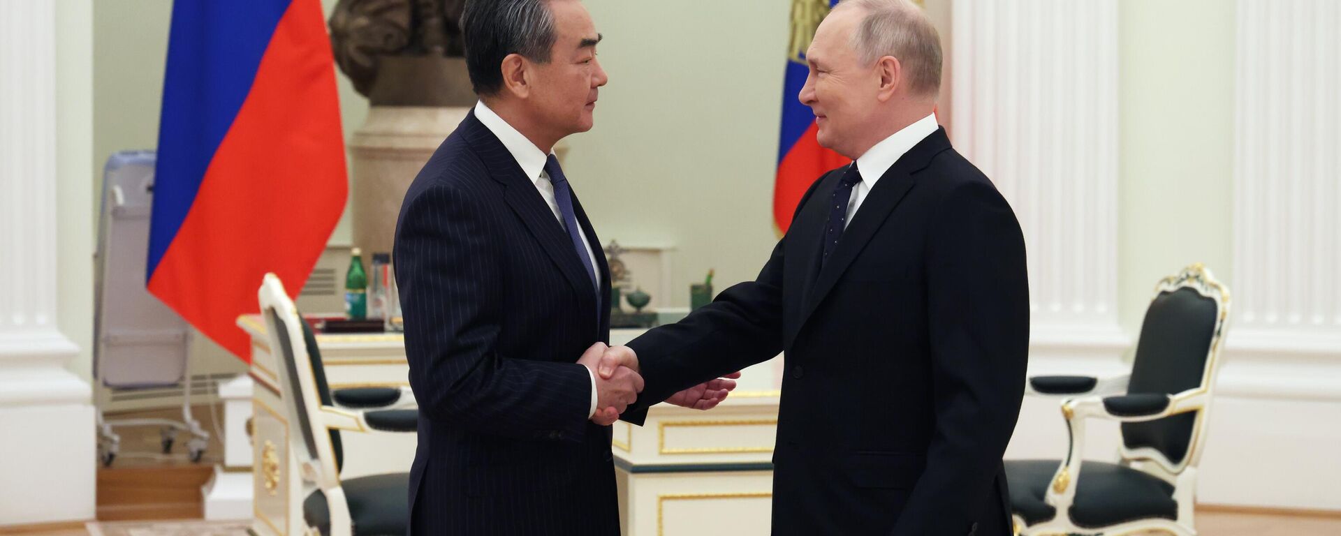 Vladimir Putin, presidente da Rússia (à direita), aperta as mãos com Wang Yi, chefe da Comissão de Relações Exteriores do Comitê Central do Partido Comunista da China (à direita), 22 de fevereiro de 2023 - Sputnik Brasil, 1920, 22.02.2023