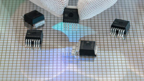 Um funcionário segura chips semicondutores sobre um wafer de 300 milímetros produzido pela empresa alemã de engenharia e eletrônica Bosch na fábrica de semicondutores da Bosch em Dresden, leste da Alemanha, durante o chamado TechDay da empresa em 13 de julho de 2022 - Sputnik Brasil