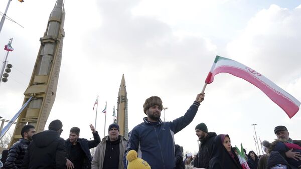 Homem acena com bandeira iraniana e mísseis no fundo durante comício anual que comemora a Revolução Islâmica de 1979 no país, em Teerã, Irã, 11 de fevereiro de 2023 - Sputnik Brasil
