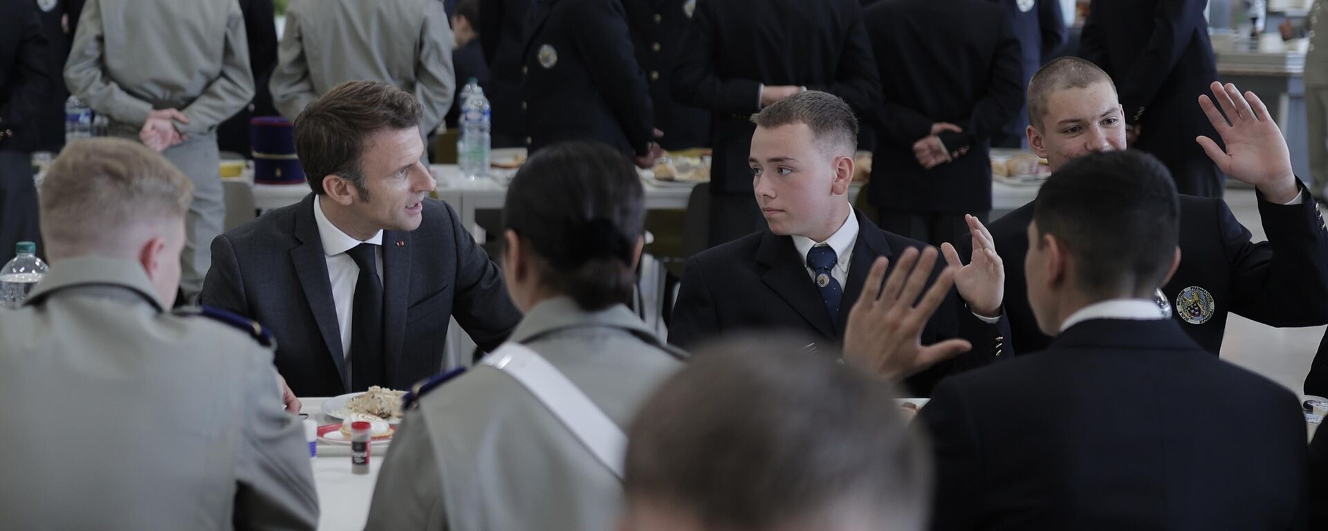 Emmanuel Macron (ao fundo da foto, à esquerda), presidente francês, fala com cadetes em escola militar de Bourges, França, em 27 de outubro de 2022, durante visitas a fábricas de defesa - Sputnik Brasil, 1920, 03.02.2025