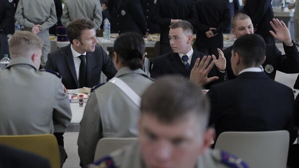 Emmanuel Macron (ao fundo da foto, à esquerda), presidente francês, fala com cadetes em escola militar de Bourges, França, em 27 de outubro de 2022, durante visitas a fábricas de defesa - Sputnik Brasil