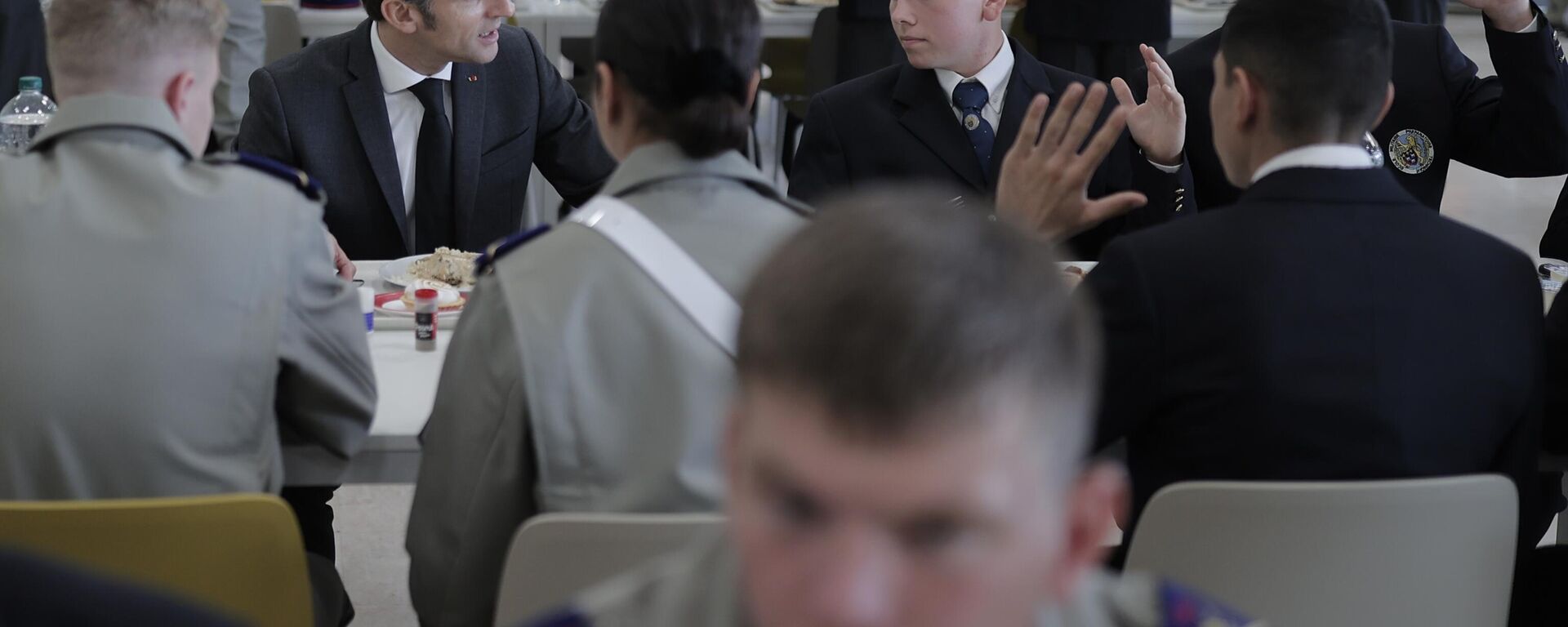 Emmanuel Macron (ao fundo da foto, à esquerda), presidente francês, fala com cadetes em escola militar de Bourges, França, em 27 de outubro de 2022, durante visitas a fábricas de defesa - Sputnik Brasil, 1920, 03.02.2025