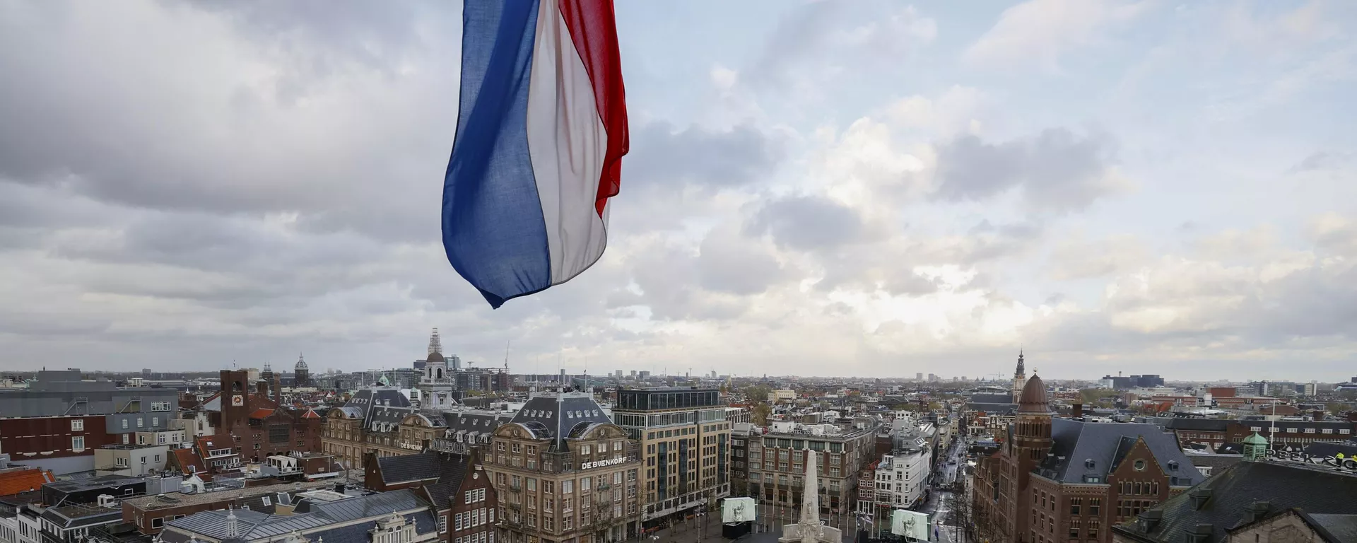 Bandeira holandesa hasteada a meio mastro sobre a Praça Dam, desprovida de espectadores devido a restrições relacionadas ao coronavírus, enquanto o rei holandês Willem-Alexander e a rainha Maxima depositam uma coroa de flores durante uma cerimônia nacional para comemorar os mortos da guerra em Amsterdã, Países Baixos, na terça-feira, 4 de maio de 2021. - Sputnik Brasil, 1920, 02.09.2024