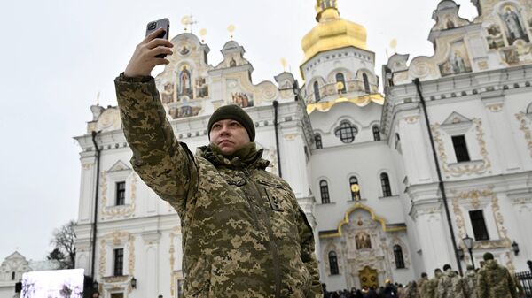 Militar ucraniano faz selfie frente ao Mosteiro da Sagrada Dormição de Kiev-Pechersk, em Kiev, Ucrânia, 7 de janeiro de 2023 - Sputnik Brasil