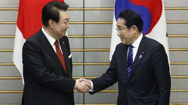 O presidente da Coreia do Sul, Yoon Suk Yeol (E), e o primeiro-ministro do Japão, Fumio Kishida, apertam as mãos antes de uma reunião de cúpula na residência oficial do primeiro-ministro em Tóquio, 16 de março de 2023 - Sputnik Brasil
