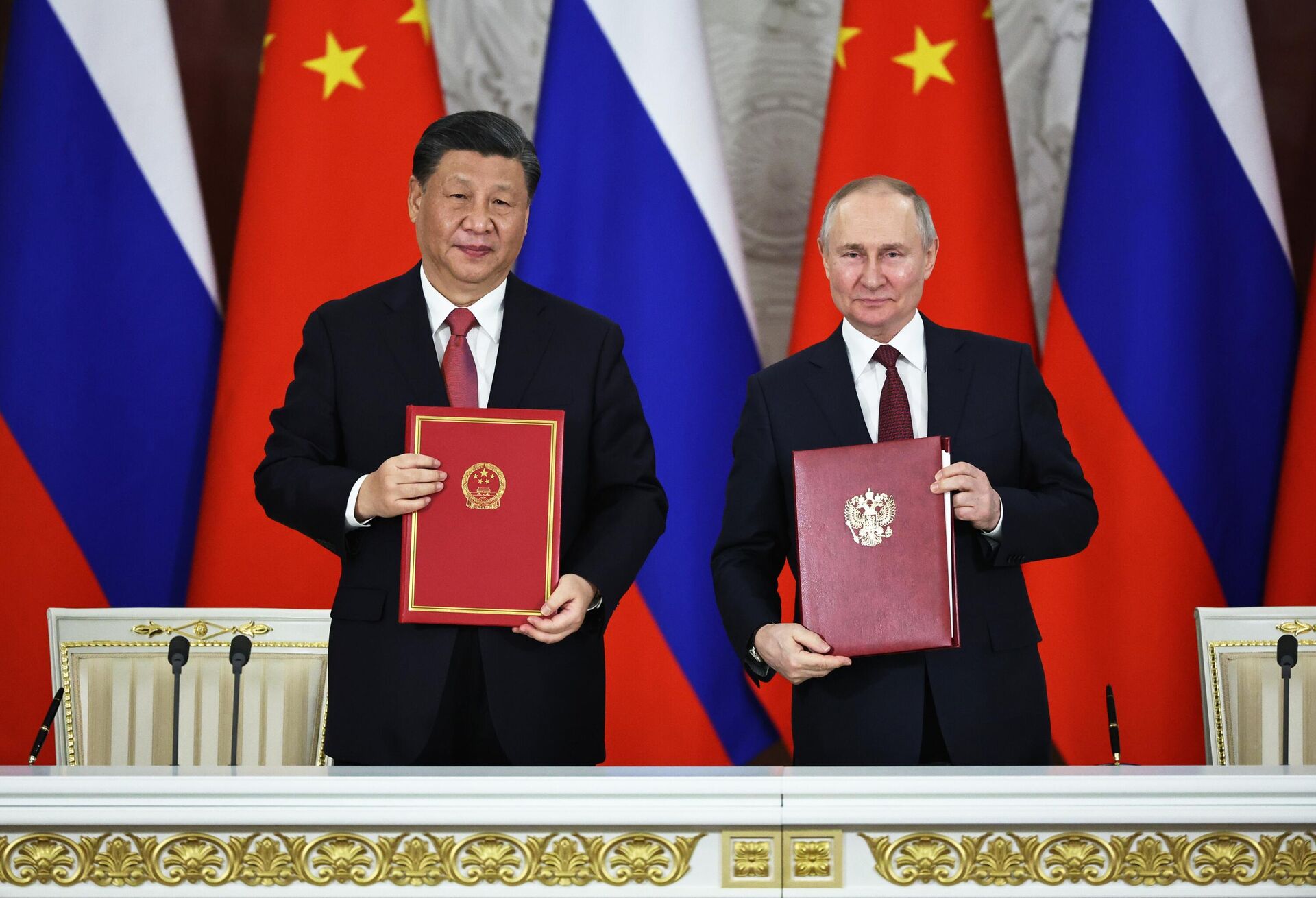 O presidente chinês Xi Jinping e o presidente russo Vladimir Putin se cumprimentam após a assinatura de uma declaração conjunta sobre o aprofundamento da parceria abrangente e cooperação estratégica e sobre o plano de desenvolvimento de áreas-chave da cooperação econômica até 2030 no Kremlin, em Moscou, Rússia - Sputnik Brasil, 1920, 24.03.2023