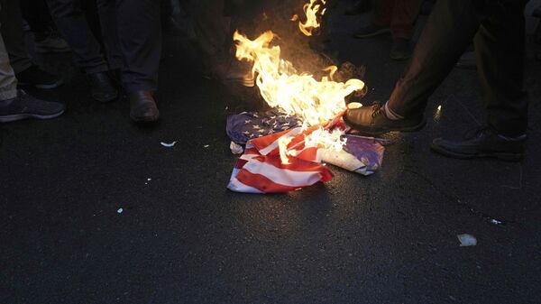 Manifestantes iranianos queimam a bandeira dos EUA durante protesto contra caricaturas publicadas pela revista satírica francesa Charlie Hebdo, em frente à embaixada da França em Teerã. Irã, 11 de janeiro de 2023 - Sputnik Brasil