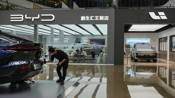 Trabalhador limpa um modelo do carro Rising F7 em uma seção que vende várias marcas de carros elétricos de fabricação chinesa dentro de um shopping em Pequim, 4 de abril de 2023. - Sputnik Brasil