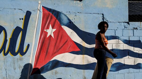 Uma mulher passa por uma parede pintada com a bandeira cubana com a legenda continuidade em Havana, 7 de fevereiro de 2023 - Sputnik Brasil