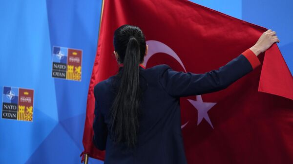 Membro da delegação da Turquia ajusta a bandeira antes de um discurso do presidente turco Recep Tayyip Erdogan durante cúpula da OTAN em Madri, Espanha, 30 de junho de 2022 - Sputnik Brasil