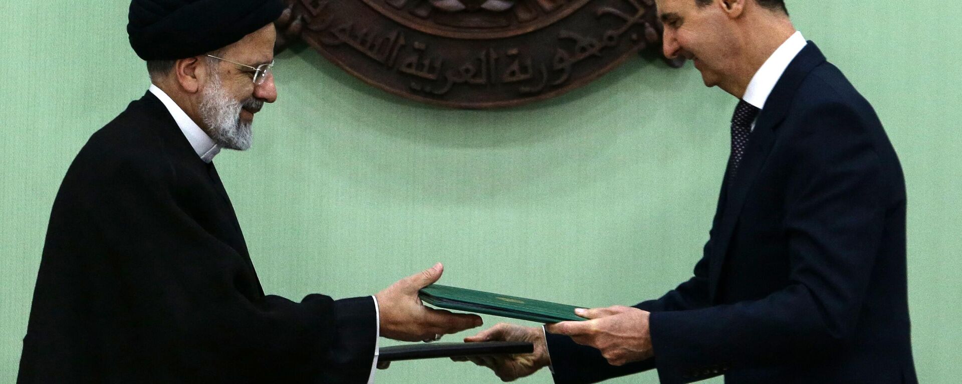 O presidente da Síria, Bashar al-Assad (à direita), e seu colega iraniano, Ebrahim Raisi, trocam documentos após assinarem um memorando de entendimento sobre cooperação estratégica de longo prazo em Damasco, em 3 de maio de 2023 - Sputnik Brasil, 1920, 03.05.2023