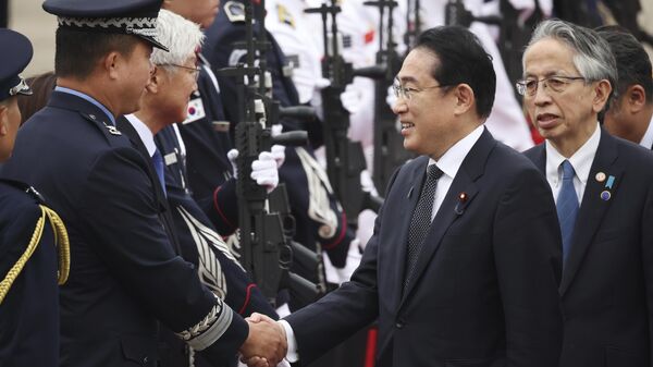 O primeiro-ministro japonês Fumio Kishida, à direita, é recebido por um oficial militar sul-coreano em sua chegada à base aérea de Seul, Coreia do Sul, 7 de maio de 2023. - Sputnik Brasil