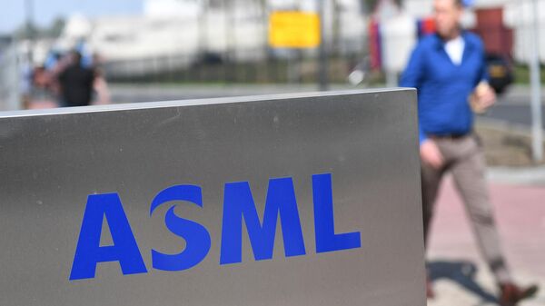 Empregado da empresa de semicondutores ASML passa ao lado de seu logotipo em Veldhoven, Países Baixos, 17 de abril de 2018 - Sputnik Brasil