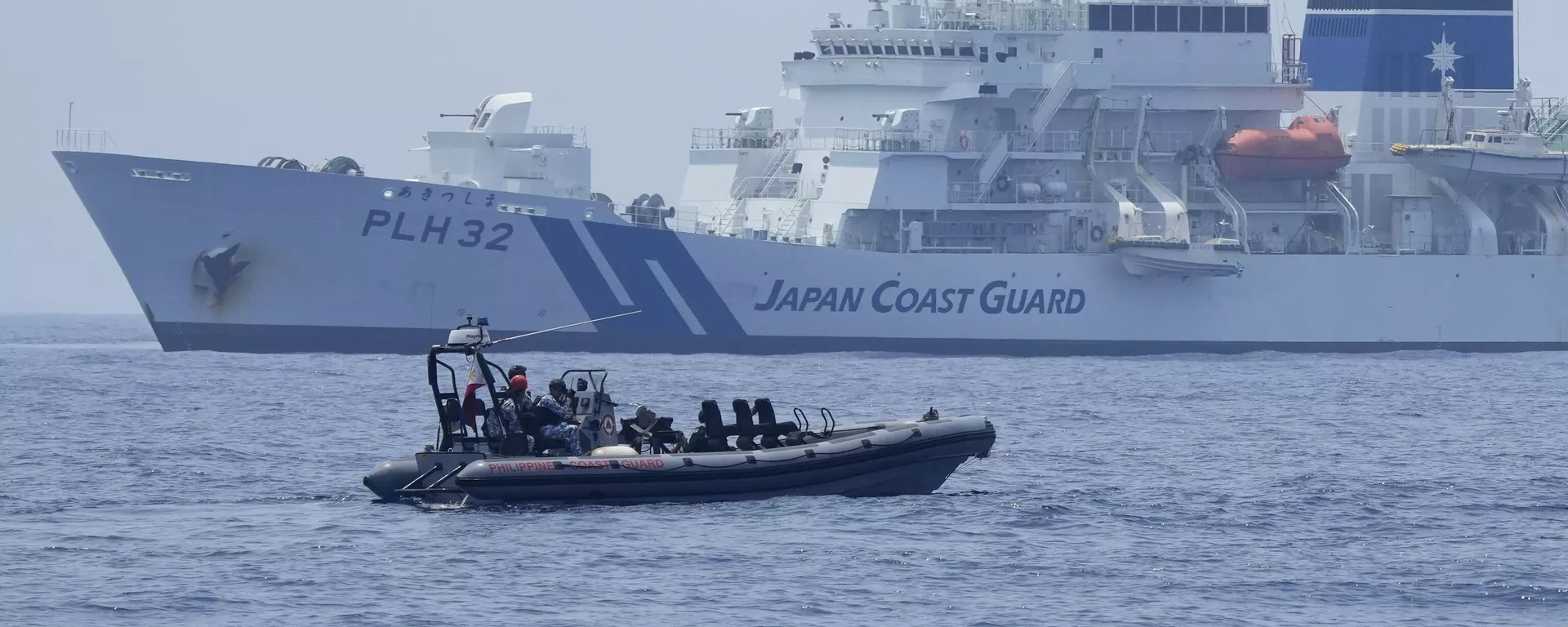 Um barco inflável de casco rígido da Guarda Costeira filipina passa pela Guarda Costeira Japonesa Akitsushima (PLH-32) durante uma perfuração trilateral da Guarda Costeira nas águas na província de Bataan, Filipinas, terça-feira, 6 de junho de 2023 - Sputnik Brasil, 1920, 16.08.2024