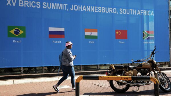 Mulher passa por cartaz do lado de fora do local da Cúpula do BRICS 2023, no Centro de Convenções de Sandton, em Sandton, Joanesburgo, África do Sul, 20 de agosto de 2023 - Sputnik Brasil