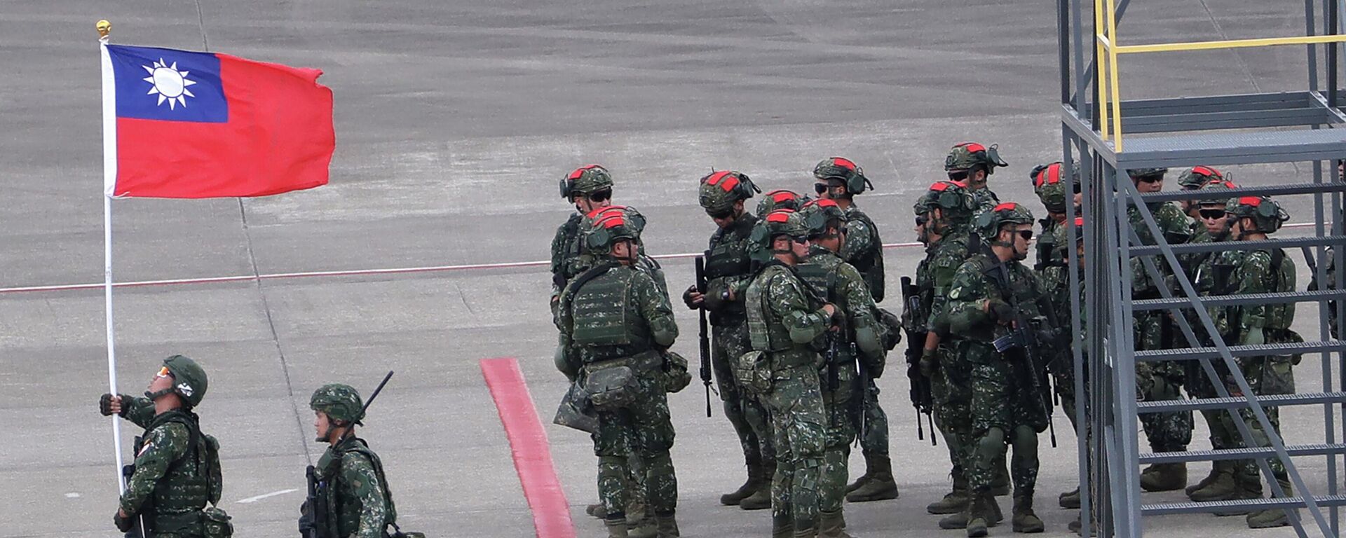 Um soldado taiwanês segura uma bandeira nacional de Taiwan perto de um grupo de soldados com marcas vermelhas em seus capacetes para desempenhar o papel de inimigo durante os exercícios militares anuais de Han Kuang, simulando um ataque a um campo de aviação no Aeroporto Internacional de Taoyuan, em Taoyuan, norte de Taiwan, julho 26, 2023 - Sputnik Brasil, 1920, 23.02.2024