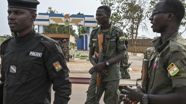 Oficiais da Polícia Nacional do Níger montam guarda enquanto apoiadores do Conselho Nacional de Salvaguarda da Pátria (CNSP) do Níger protestam do lado de fora do Níger e da base aérea francesa em Niamey em 30 de agosto de 2023  - Sputnik Brasil