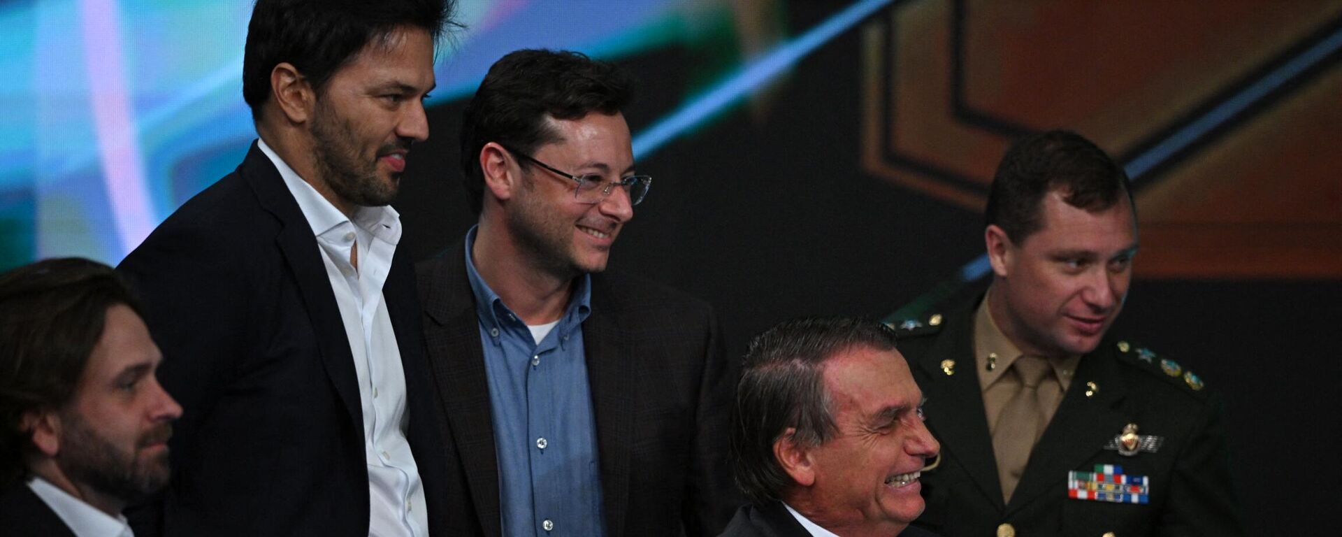 O presidente e candidato à presidência do Brasil, Jair Bolsonaro, sorri enquanto o ministro das Comunicações, Fabio Faria, e o coordenador de comunicação de sua campanha à reeleição, Fabio Wajngarten, ficam atrás dele durante entrevista transmitida pela emissora SBT em Osasco, região metropolitana de São Paulo, Brasil, em 21 de outubro de 2022 - Sputnik Brasil, 1920, 01.09.2023