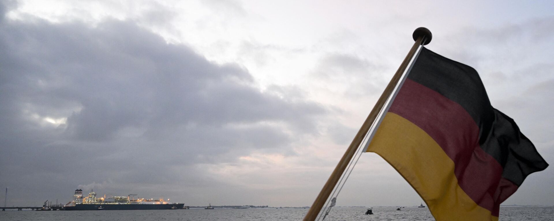 A bandeira nacional alemã tremula enquanto o navio Hoegh Esperanza da Unidade Flutuante de Armazenamento e Regaseificação atraca no terminal de Gás Natural Liquefeito (GNL) no porto de Wilhelmshaven, norte da Alemanha, 15 de dezembro de 2022 - Sputnik Brasil, 1920, 04.09.2023