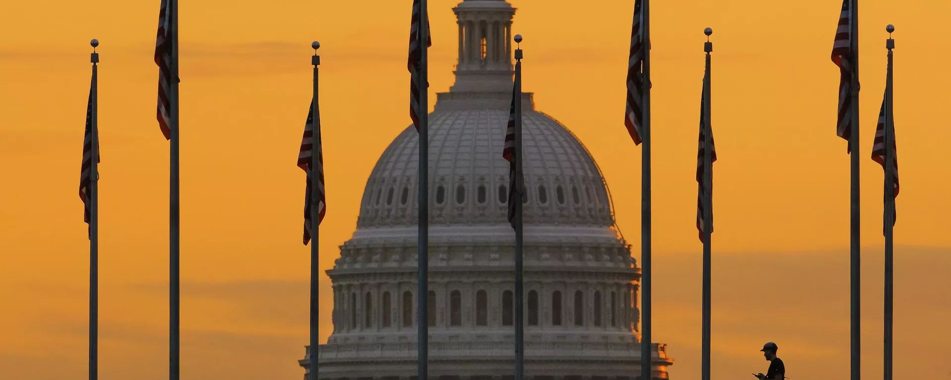 Pedestre caminha ao nascer do sol por bandeiras dos EUA no National Mall e passa pelo edifício do Capitólio norte-americano, em Washington D.C. EUA, 7 de novembro de 2022 - Sputnik Brasil, 1920, 03.12.2024